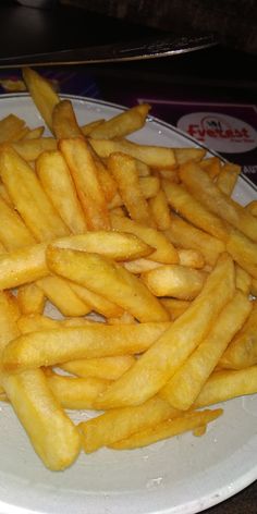 a white plate topped with french fries on top of a table