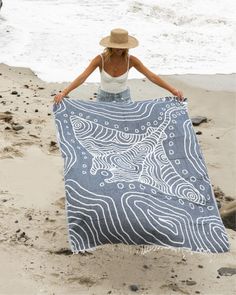 a woman on the beach with a blue and white blanket