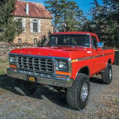 an old red truck parked in front of a house