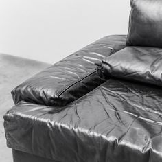 a black leather couch with two pillows on it's back and the seat folded down