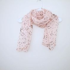 a pink scarf with musical notes on it hanging from a white hanger against a white wall