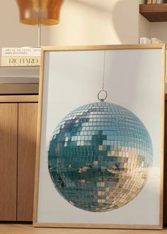 a mirror ball hanging from a wooden frame on a table next to a book shelf