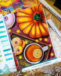 an open notebook with some food on it next to markers and pencils in the background