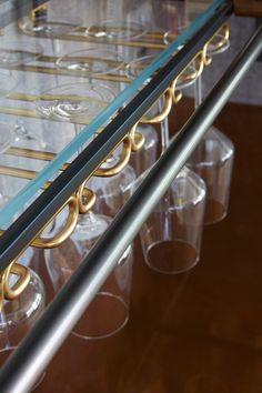 several clear cups are lined up on a glass shelf with gold trim around the edges