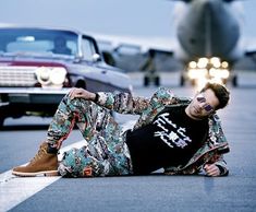 a man laying on the ground next to an airplane