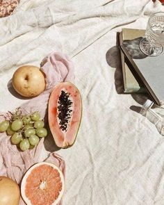 a table topped with sliced up fruit and wine glasses on top of a white cloth