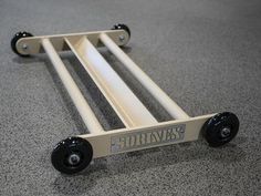 a white and black cart with wheels on the floor next to a gray carpeted floor