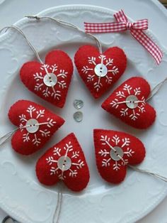 red hearts with snowflakes on them are hanging from a white plate that is decorated with ribbon