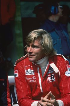 a man sitting on top of a white bench next to another man wearing a red jacket