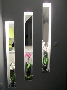 three vases filled with flowers sit in front of two mirrors on the wall next to each other