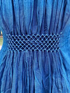 the back of a blue dress with beads on it