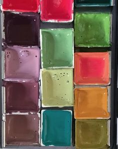 a close up of many different colored squares in a box with paint on it's sides