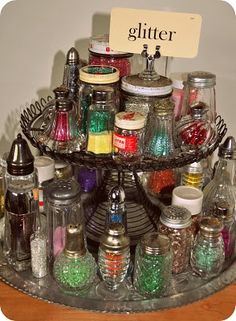 there is a tray that has many jars on it and a sign with the word glitter