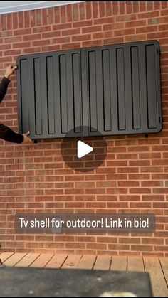 a man standing next to a brick wall with a black box on it's side