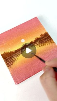 someone is painting a sunset scene with acrylic paint on the canvas and using a marker