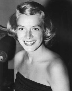 an old black and white photo of a woman with short hair smiling at the camera