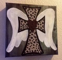 an angel cross with white wings painted on the wall next to a brown leopard print