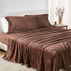 a bed covered in brown sheets and pillows