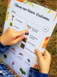 a person holding up a poster with different types of plants and animals on it in their hands