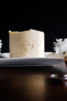 a piece of cake sitting on top of a white plate next to flowers and spoons