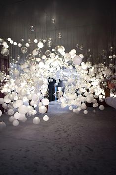 a room filled with lots of white balloons floating in the air and hanging from the ceiling