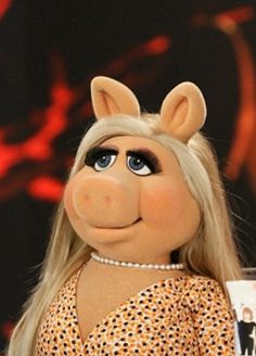 the miss piggy doll is holding a drink in her hand and looking at the camera