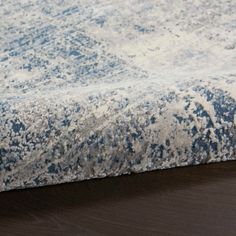 a blue and white rug on top of a wooden table next to a black surface