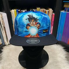 a dragon ball cap sitting on top of a black hat stand in front of a bookshelf