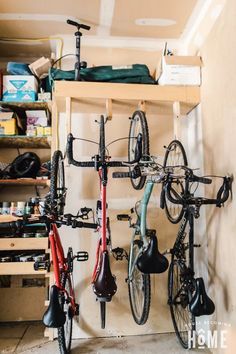 there are many bikes that are hanging on the wall in this room, and one is also attached to the bike rack