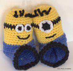 two crocheted yellow and blue slippers with eyes on each side, one has black eyeballs