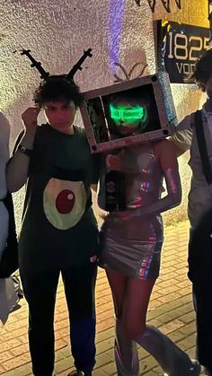 three people dressed up in costumes and one is holding an old fashioned computer box with the word'alien'on it