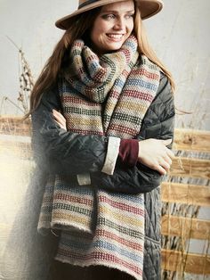 a woman wearing a hat and scarf with her arms crossed