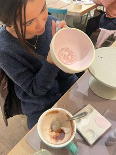 a woman sitting at a table with a bowl and spoon in her hand