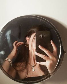 a woman taking a selfie in front of a mirror with her cell phone up to her face