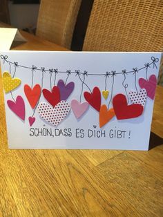 a card with hearts hanging on a clothes line and the words schon - daas es dich git