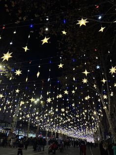 many people are walking around with lights strung from the ceiling