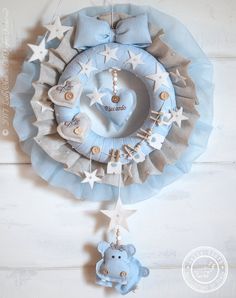 a blue teddy bear hanging from the side of a wreath with stars and moon decorations