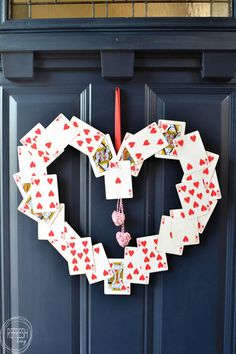 a heart shaped playing cards hanging on a blue door with the word love spelled in it