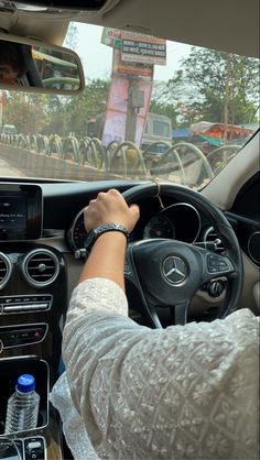 a person driving a car with their hand on the steering wheel and other vehicles in the background