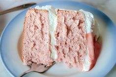 a piece of pink cake with white frosting on a plate next to a fork