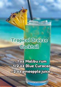 a tropical breeze cocktail on a wooden table next to the ocean with text that reads tropical breeze cocktail, malbu rum, 12oz blue curaco, pineapple juice