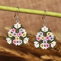 Feel the caress of the spring season with these blooming dangle earrings by Yanina Mirzoyan of Armenia. The artisan works with glass beads in a palette of green and pastel hues, which allow her to recreate the region's floral scapes. The earrings, in a stylish triangle shape, have comfortable sterling silver hooks. Pastel Jewelry, Glass Beads Jewelry, Beaded Earrings Patterns, Earring Ideas, Mens Jewelry Necklace, Geometric Jewelry, Pastel Hues, Beaded Dangle Earrings, Floral Jewellery