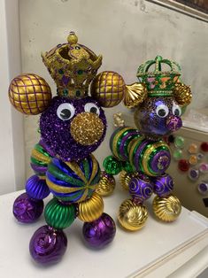 two colorful ornaments are sitting on top of a white shelf in front of a window