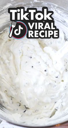 a metal bowl filled with white frosting on top of a wooden table