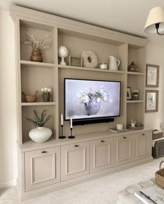 a large flat screen tv sitting on top of a wooden shelf in a living room