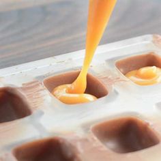 an orange liquid is being poured into some chocolate