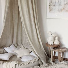 an unmade bed with white linens and pillows on the floor next to a wooden table