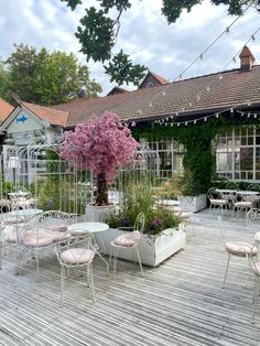 tables and chairs are set up outside on the wooden floored patio with pink flowers