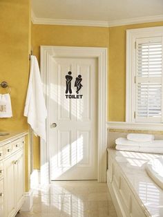 there is a bathroom with yellow walls and white furniture in it, along with towels on the counter