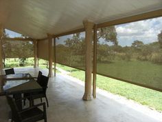 a covered patio with tables and chairs on the side walk in front of grass field